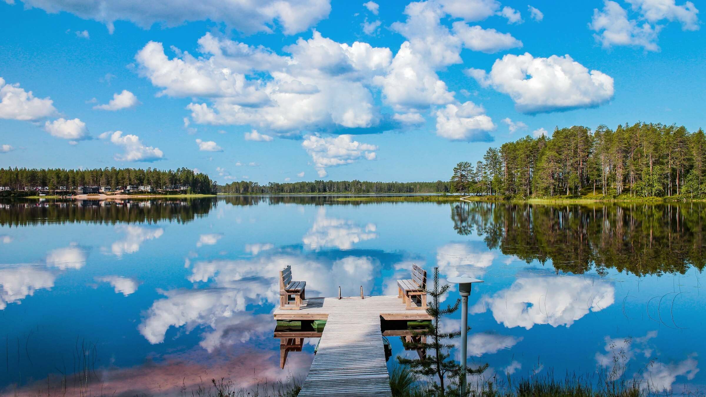 Laituri tyynellä järvellä, jonka pinnasta heijastuvat kesän pilvet, Hossa